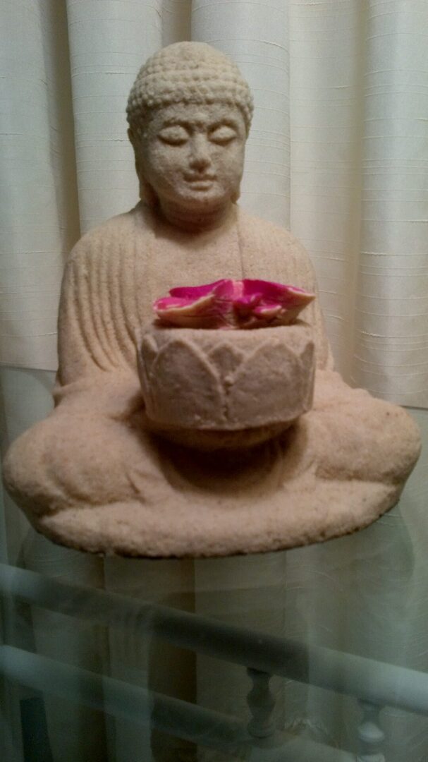 A statue of buddha holding a flower in it's lap.