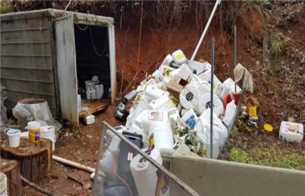 A dumpster full of trash next to a door.